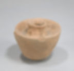 Ancient clay vessel with a small neck and wide base, set against a plain gray background. The pottery appears weathered and textured.
