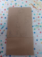 Brown cardboard with pencil sketch of abstract figures on a polka dot background. The table has scattered paint splatters.