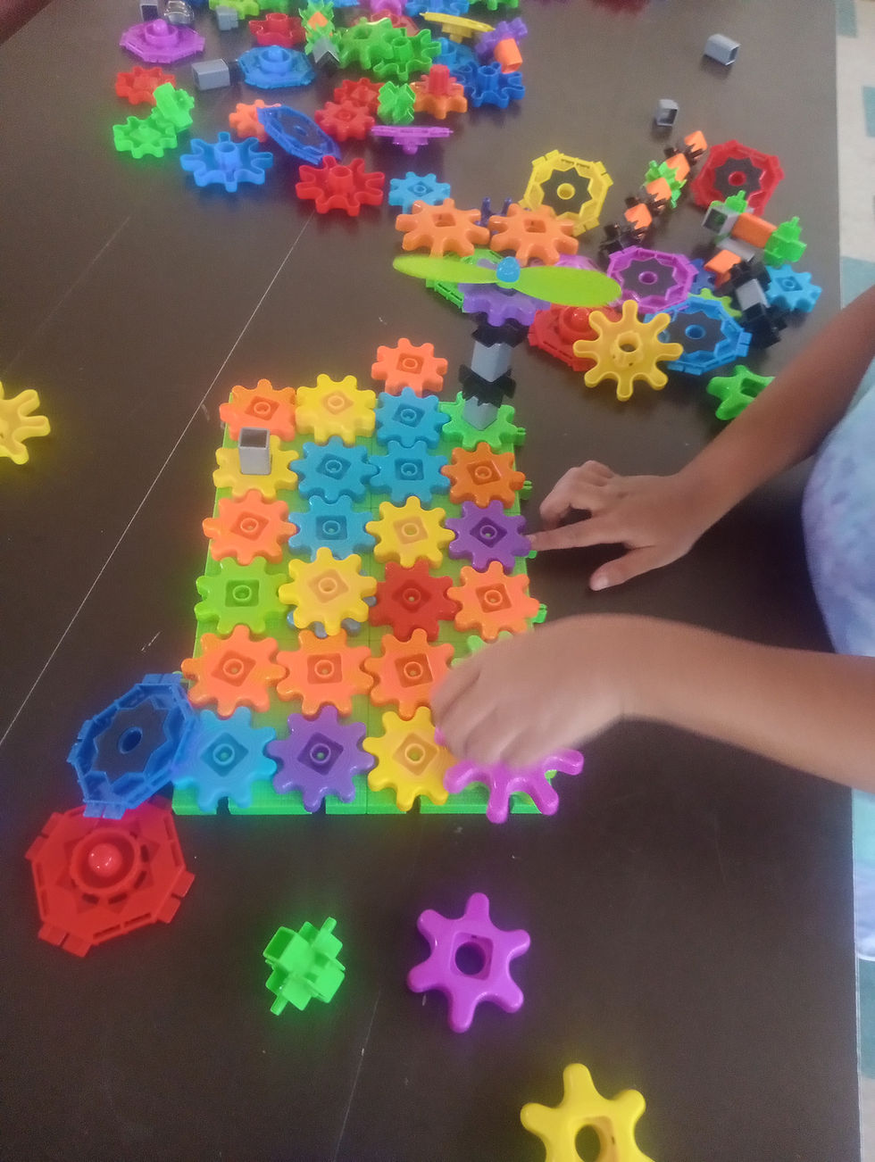 Child turning displaying fine motor skills as she turns a gear toy
