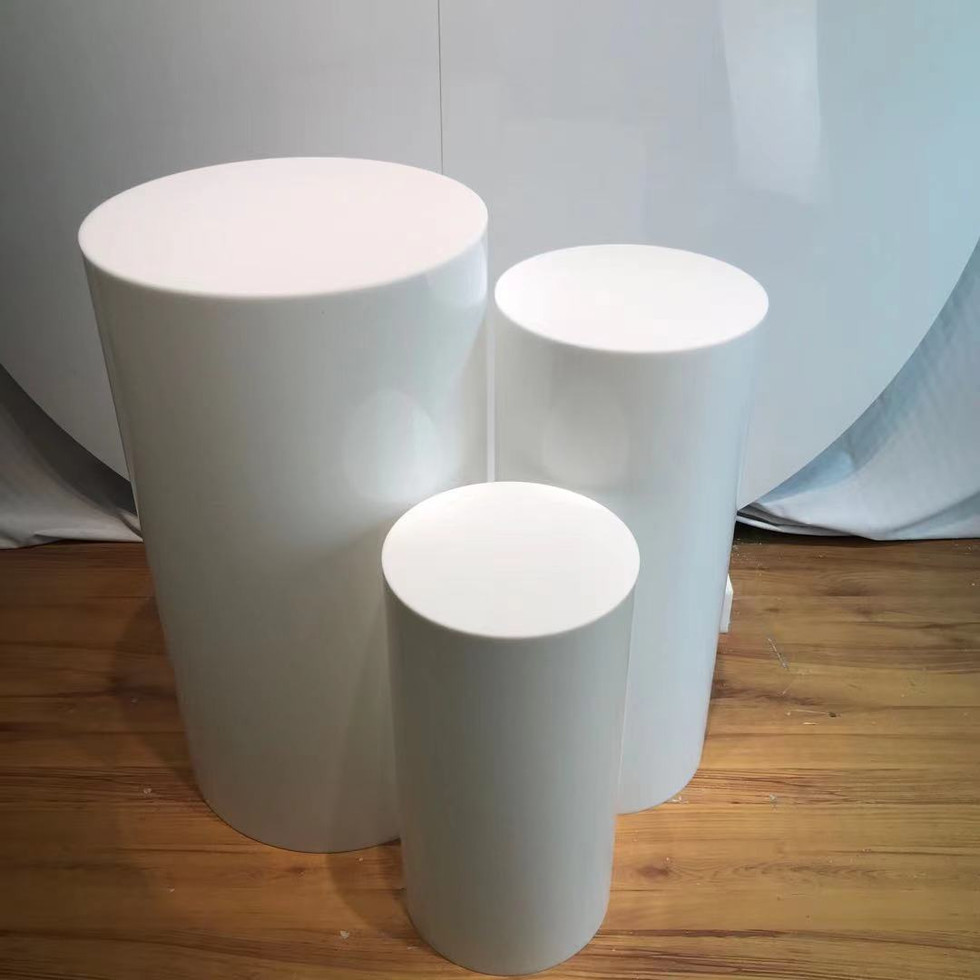 Three white cylindrical displays on wood floor
