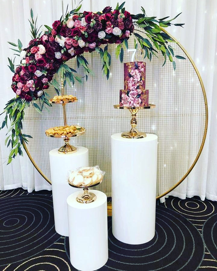 Elegant 70th birthday dessert display with floral arch