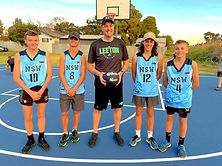Four youth leaders standing with basketball coach wearing blue basketball singlets