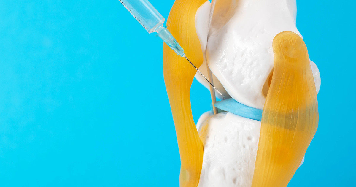 A pain specialist using ultrasound guidance to perform a joint injection while explaining the procedure to a patient.