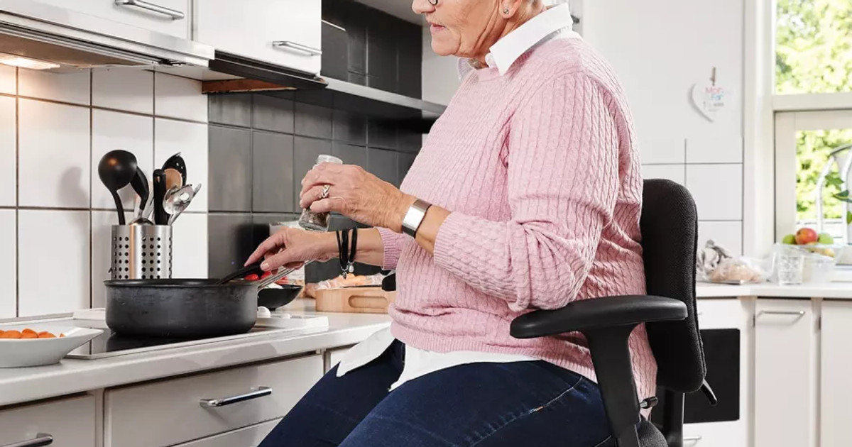 A person preparing a meal using simple adaptations and assistive equipment to reduce effort and remain independent while living with persistent pain.