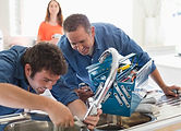 Two men with tools fixing a kitchen sink.