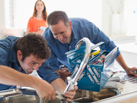 A plumber working in a kitchen