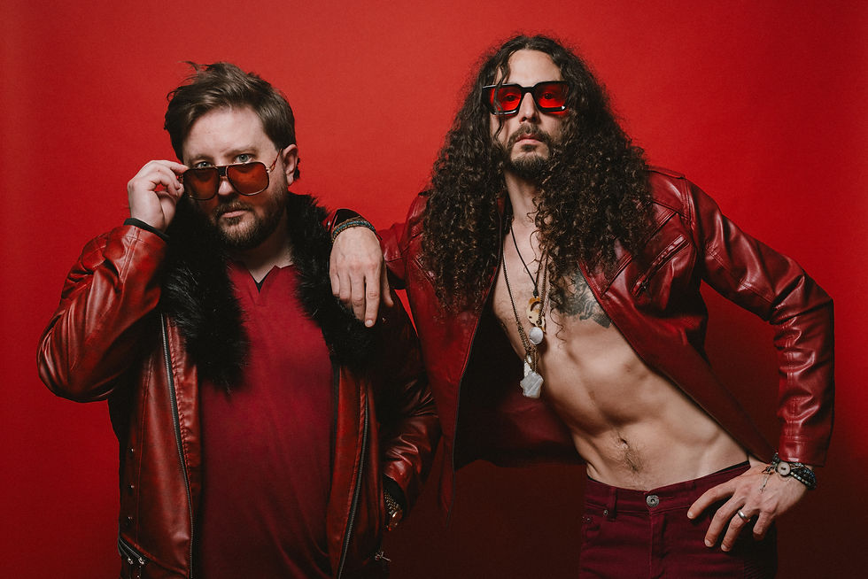 Two men in red leather jackets and sunglasses pose confidently against a red background. One adjusts his glasses, both exude a retro vibe. HIVESONG - The Cage, a music blog powered by Cage Riot
