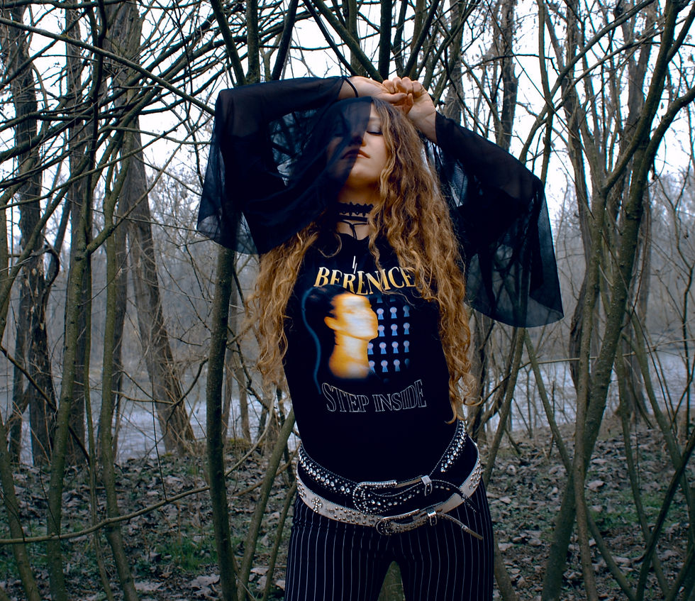 Woman with long hair poses in a wooded area, wearing a "Berenice Step Inside" shirt. Her eyes are closed, and arms are raised, creating a serene mood. Berenice - The Cage, a music blog powered by Cage Riot