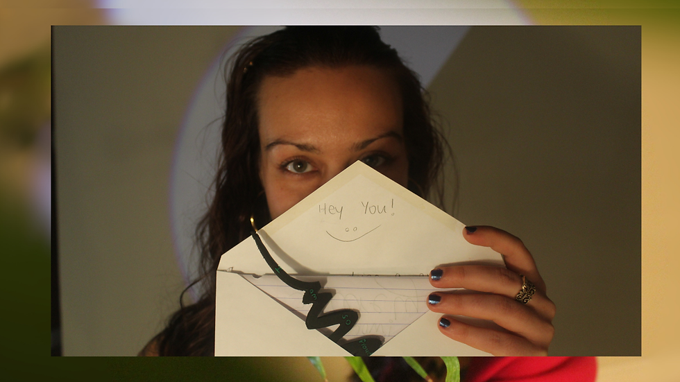 Woman holding an open envelope with "Hey You!" written. Smiling face doodle. Dim background, playful mood. Navy nails. Morgan Mikenas Music - The Cage, a music blog powered by Cage Riot