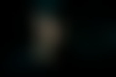 A man with a beard and cap gazes downward in low light. Dark background; mood is contemplative. No visible text or notable colors. Seth Schaeffer - The Cage, a music blog powered by Cage Riot