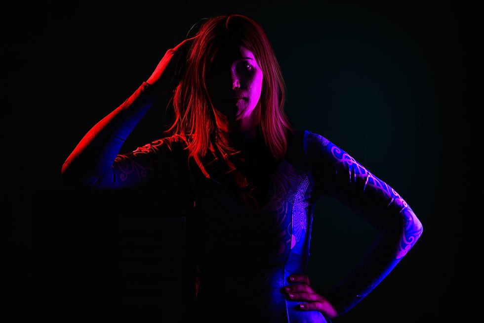 Silhouetted person in a dark setting with neon red and blue lights, hand on head; intricate patterns on clothing; mysterious mood. SERAh - The Cage, a music blog powered by Cage Riot