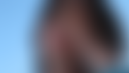 A person with long hair covers their face with one hand, eyes closed, appearing pensive against a clear blue sky. Byome* - The Cage, a music blog powered by Cage Riot