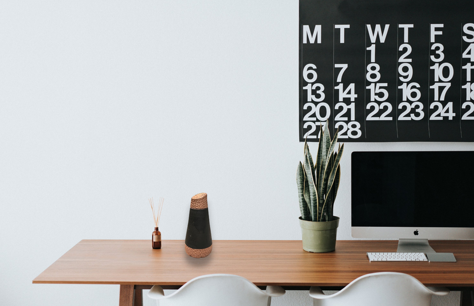 Black conical water bottle with hammered copper sitting on desk with large calendar in background