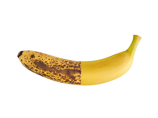 A banana is half ripe with brown spots and half yellow, against a white background. The split color highlights the ripening stages.