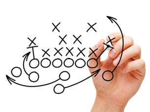 Hand drawing a football tactic diagram with X's and O's on a transparent surface, white background, illustrating strategic planning.