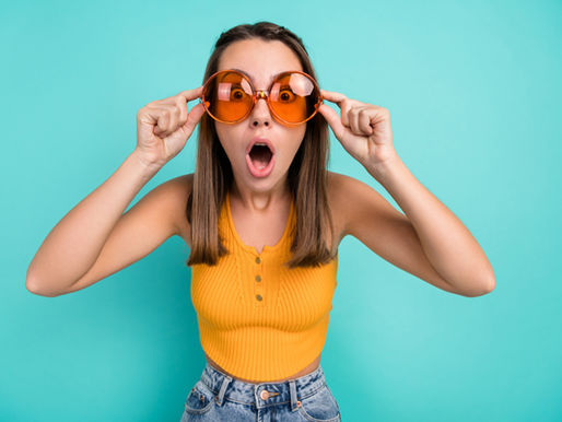 Surprised woman wearing sunglasses on a teal background