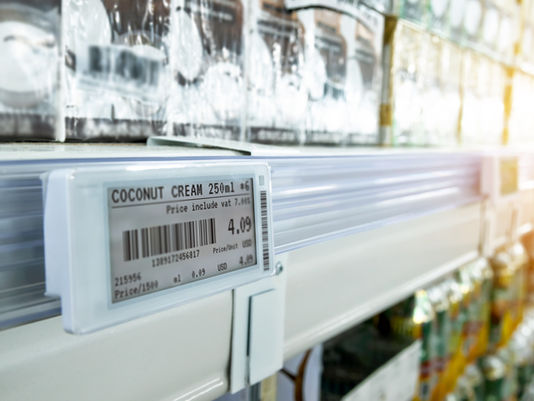 Price tag for coconut cream, 250ml, $4.09, on a grocery shelf. Blurred products in the background with bright lighting