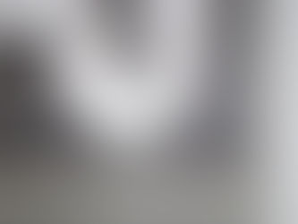 Leaking white PVC pipe joint spraying water indoors against a gray wall, with splashes and droplets everywhere