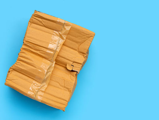 Crushed cardboard box with tape on a vibrant blue background, showing creases and texture, creating a minimalist and gritty look.