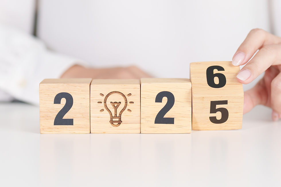 Hands are changing wooden blocks from 2025 to 2026 on a white surface. A lightbulb icon is engraved on the second block.