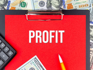 Red clipboard with "PROFIT" text, calculator, pen, and US dollar bills.