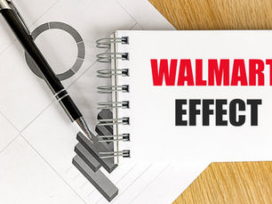 A spiral notebook with "WALMART EFFECT" in bold red and black text lies on a wooden surface, next to a black pen and geometric sheet.