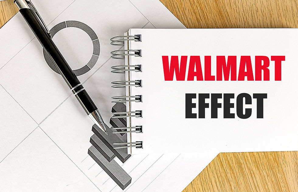 A spiral notebook with "WALMART EFFECT" in bold red and black text lies on a wooden surface, next to a black pen and geometric sheet.