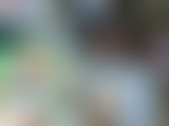 Employee in an apron uses a tablet in a grocery aisle, surrounded by colorful packaged goods. Focused expression, store setting.