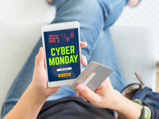 Person shopping online for Cyber Monday deals on a smartphone. They hold a credit card, wearing casual jeans in a cozy setting.