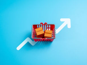 Red shopping basket with two boxes on blue background, white upward arrow suggesting growth or rising sales
