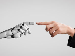 Human and robot hands nearly touch against a gray background, symbolizing connection between humanity and technology. Elegant, futuristic mood.