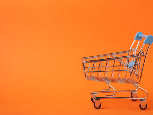 Mini shopping cart with blue handles on an orange background, creating a vibrant contrast. No text visible.