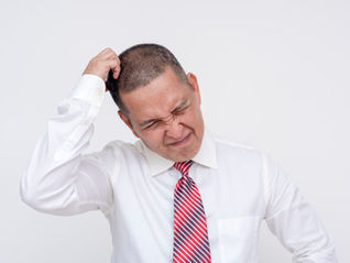 Man in white shirt and red-striped tie scratching head with a confused expression against a plain white background.