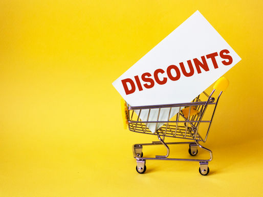 A shopping cart holds a white card with "DISCOUNTS" in red text against a vibrant yellow background, suggesting a sales promotion.