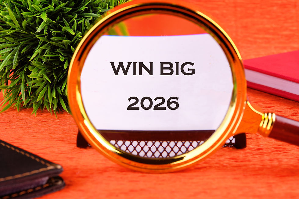 Magnifying glass on red surface focuses on text "WIN BIG 2026." Green plant and red notebook in background suggest motivation.