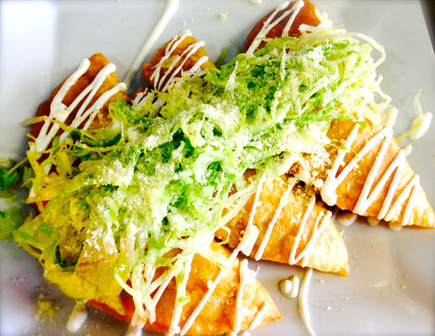 Golden quesadillas topped with shredded lettuce and crema