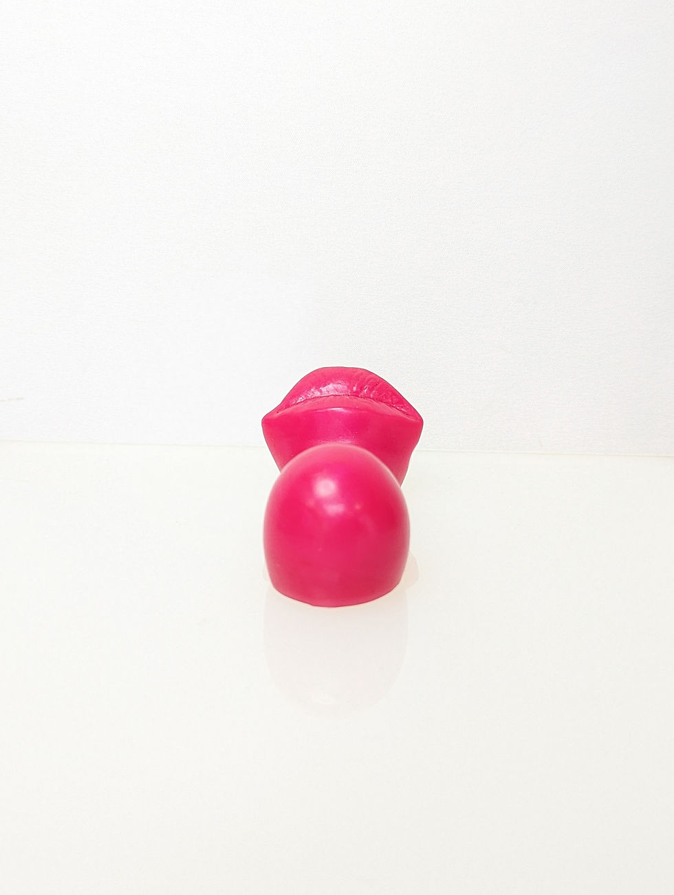 Thumbnail: End on view of a pink silicon ride on grinder with lips facing up, bulbous end, and a dip for pubic bone comfort