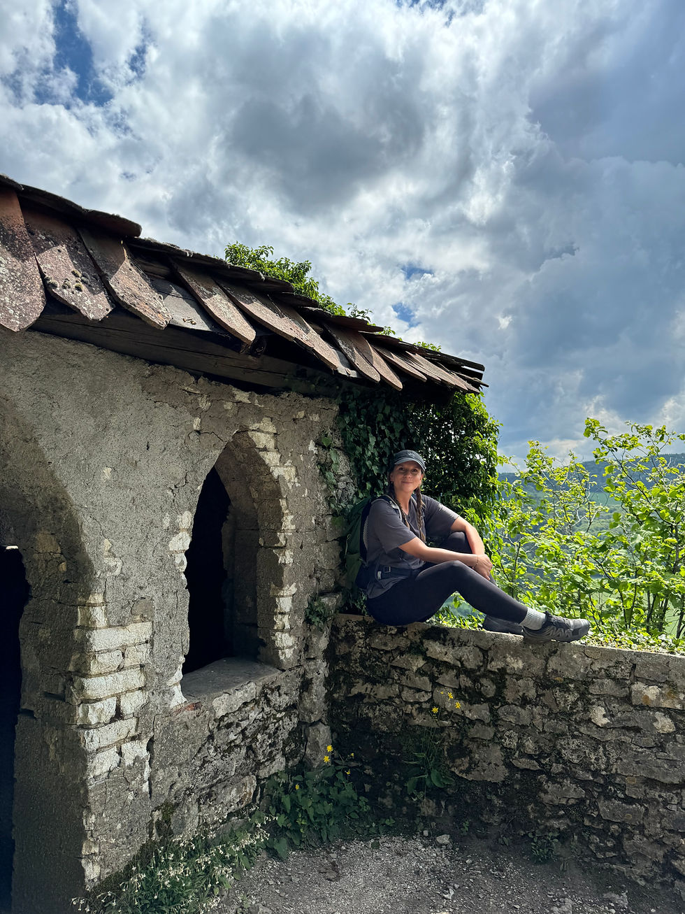 Eine Frau sitzt auf Mauer von Burgruine