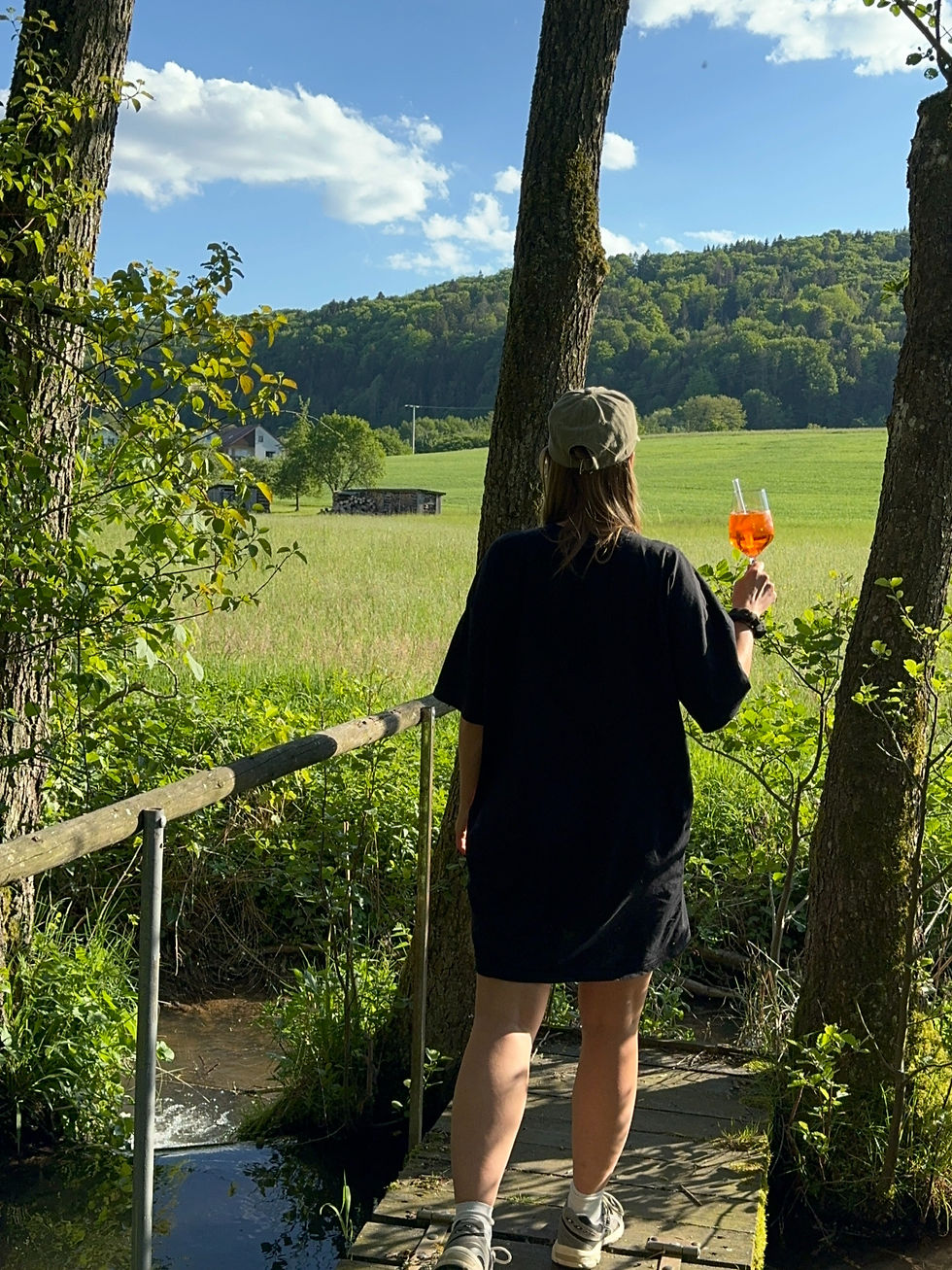 Eine Frau, die mit Aperol Spritz in die Ferne schaut