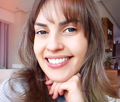 Biomédica da clinica sorrindo com a mão esquerda destacando seu rosto