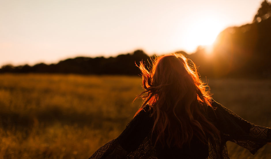 Ragazza che funziona nel campo al tramon