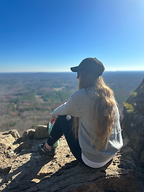 A picture of the therapist sitting on a mountain pearing out