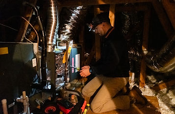 A picture of a technician from Testa Care servicing a furnace in an attic