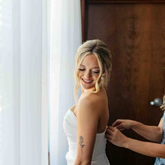 Bride gets her wedding dress zipped up.