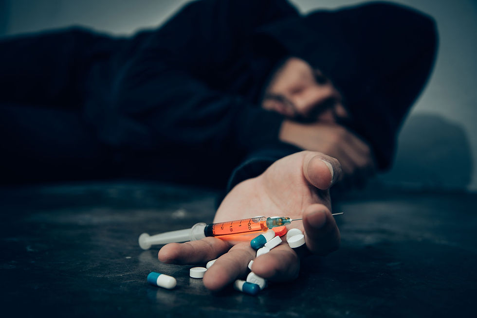 Person struggling with drug addiction lying on the floor with syringe and pills, symbolizing the urgent need rehabilitation