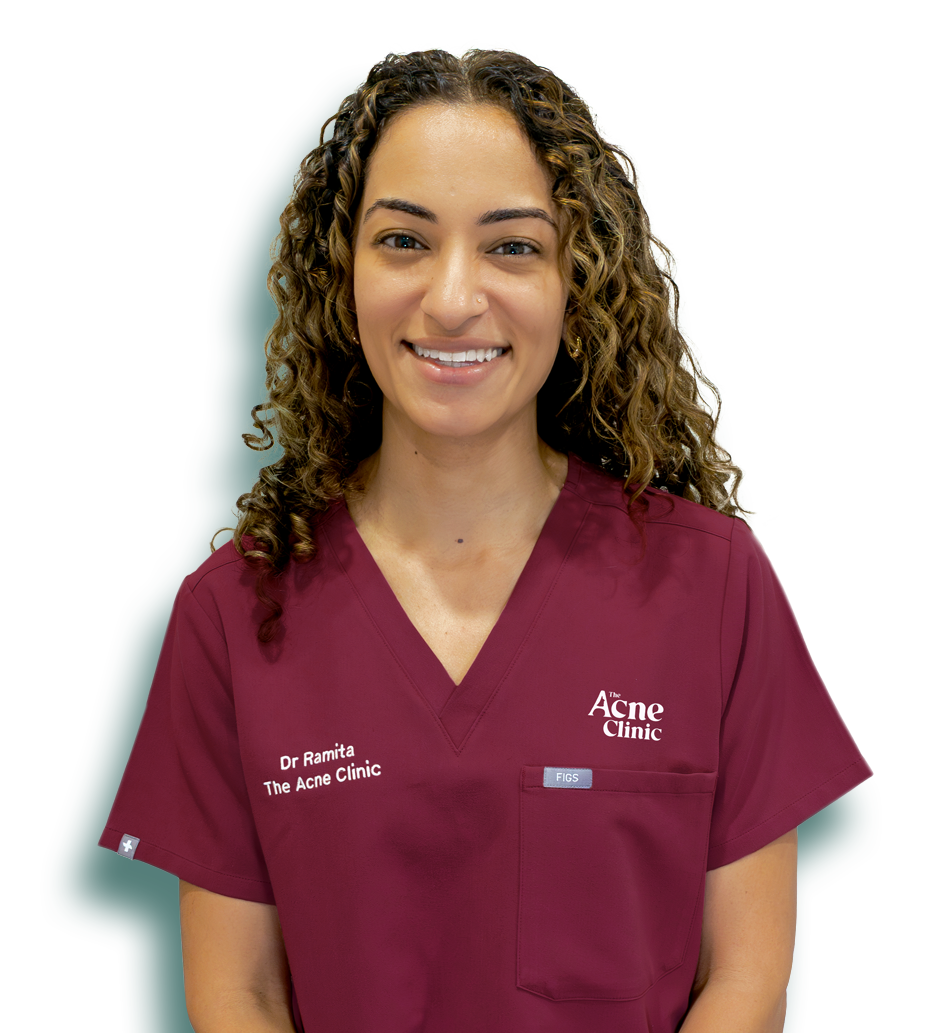 Dr Ramita Kaur Shahi, acne doctor in Singapore, at The Acne Clinic in i12 Katong, smiling in her uniform.