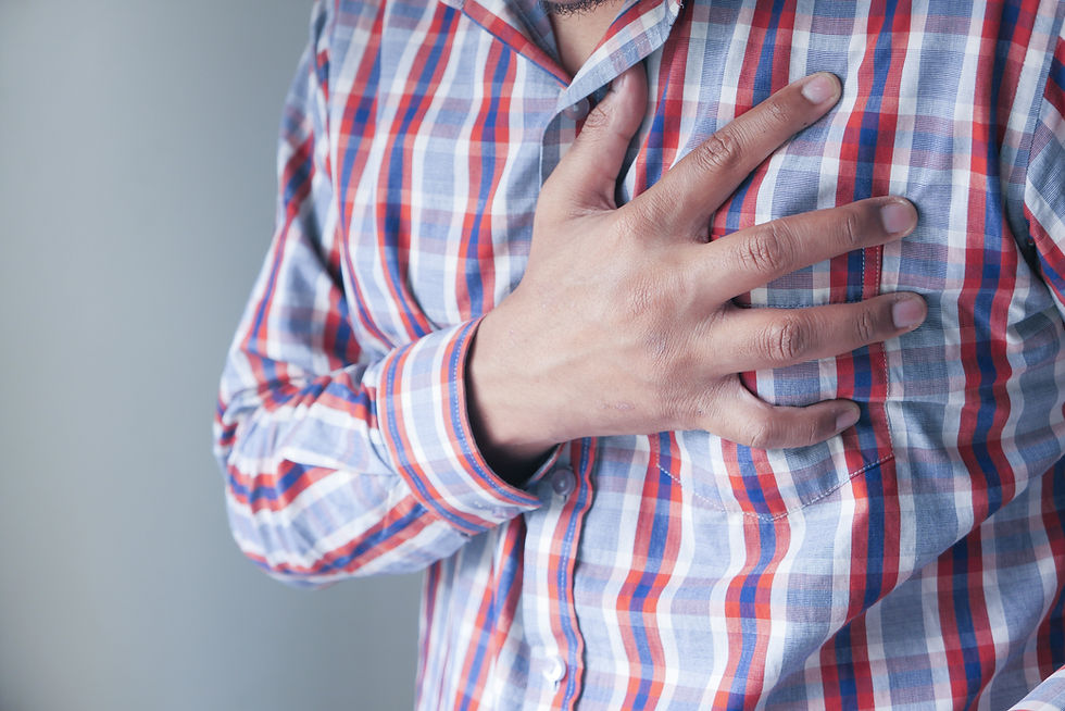A man in a checkered button-down shirt clutching his chest over his heart, showing signs of chest discomfort and irregular heart rhythm palpitations.