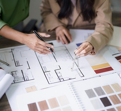 Collaborative design planning at Woodhaven Craftworks, featuring floor plans and material samples for custom projects.