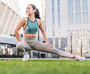 Fit woman stretching her legs outdoors on a grass field, promoting flexibility and active lifestyle.