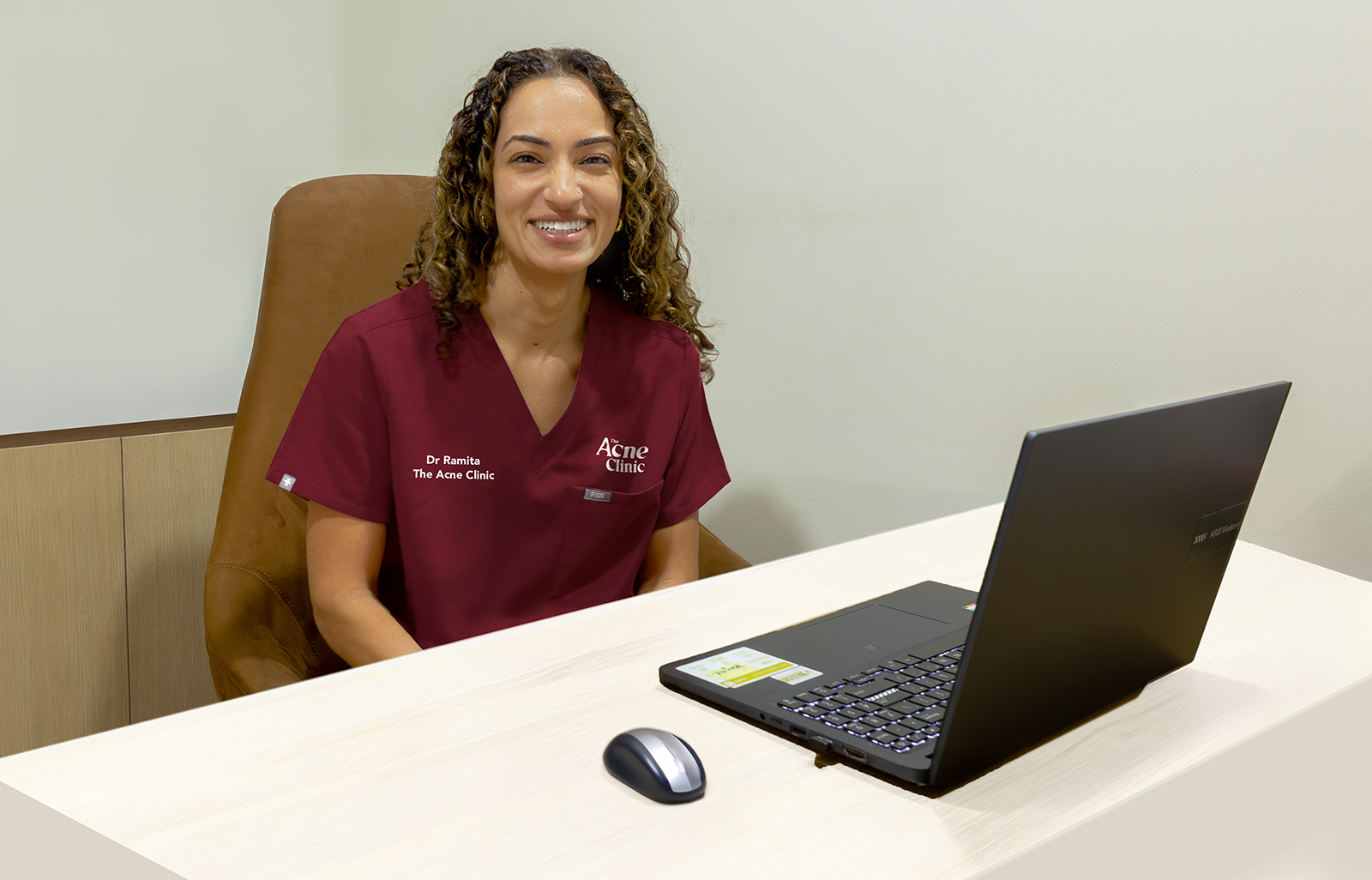 Acne doctor in Singapore seated at her desk at The Acne Clinic in i12 Katong with a laptop.